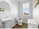 A half-bath with pedestal sink, oval mirror, wood-look floors, and window view of the neighborhood at 1828 Blue Oak Ct, Castle Rock, CO 80104