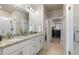 A well-lit bathroom featuring a granite countertop, double sinks, and a view into an organized walk-in closet at 420 E Fremont Pl # 309, Centennial, CO 80122