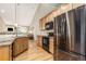 This kitchen features stainless steel appliances, granite counters, and wood cabinets, offering an open view to living area at 22163 E Calhoun Pl, Aurora, CO 80016