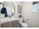 Powder room features modern vanity with round mirror, framed artwork and natural light at 18126 E Alamo Dr, Centennial, CO 80015