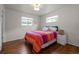 Bright bedroom featuring wood floors, white walls, two windows, and a bed with a colorful striped blanket at 886 S Jersey St, Denver, CO 80224
