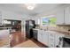 Bright kitchen featuring white cabinets, stainless steel appliances, and modern fixtures, seamlessly flowing into the dining area at 886 S Jersey St, Denver, CO 80224