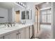 Bathroom with a double sink vanity, large mirror, and walk-in shower that leads to the bedroom at 8300 Fairmount Dr # J105, Denver, CO 80247