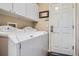 Practical laundry room with modern washer and dryer, upper cabinets, and outdoor access at 8300 Fairmount Dr # J105, Denver, CO 80247