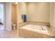 Bathroom with a jacuzzi tub and tile surround, toilet, and open doorway to an adjacent room at 8594 W Quarto Ave, Littleton, CO 80128
