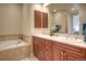Well-lit bathroom featuring a double vanity with wooden cabinets and a soaking tub with tile surround at 8594 W Quarto Ave, Littleton, CO 80128