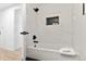 Nicely finished bathtub and shower area with dark fixtures, marble tile and storage niche at 5640 Niagara St, Commerce City, CO 80022