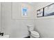 Neat bathroom featuring modern toilet and marble-style tiling on the walls at 5640 Niagara St, Commerce City, CO 80022