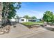 Well-maintained home featuring an expansive driveway, lush trees, and manicured front lawn at 5640 Niagara St, Commerce City, CO 80022