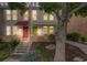 Charming townhome exterior featuring colorful awnings, a brick facade, and a landscaped front yard at dusk at 1150 Inca St # 43, Denver, CO 80204