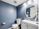 Stylish half-bathroom featuring a modern vanity, round mirror, and elegant blue walls at 15149 E Princeton Pl # D, Aurora, CO 80014