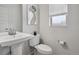 Modern bathroom with a pedestal sink, toilet, and floral wall art above the toilet at 8187 Martin Luther King Blvd, Denver, CO 80238