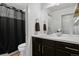 Functional bathroom with a dark vanity, a large mirror, and shower with curtain at 8187 Martin Luther King Blvd, Denver, CO 80238