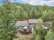 Aerial view of a grey home nestled in a lush forest, featuring a deck and an outdoor seating area at 10142 S Turkey Creek Rd, Morrison, CO 80465