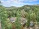 Aerial view of a grey home nestled amongst tall trees, featuring a deck and separate storage shed at 10142 S Turkey Creek Rd, Morrison, CO 80465