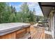 Wet wooden deck featuring a hot tub and outdoor seating area, nestled in a wooded setting at 10142 S Turkey Creek Rd, Morrison, CO 80465