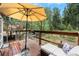 Cozy outdoor seating area with an umbrella on a wood deck, overlooking a wooded landscape at 10142 S Turkey Creek Rd, Morrison, CO 80465