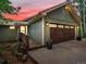 Charming home featuring a brown garage door, wood-paneled siding, and a sunset background at 30382 Kings Valley East, Conifer, CO 80433