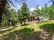 An exterior view from the backyard showcasing the tiered deck and the house through the forest trees at 30382 Kings Valley East, Conifer, CO 80433