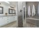 Well-lit bathroom boasts a walk-in shower with tile surround, double vanity, and modern lighting fixtures at 12513 Shore Point St, Firestone, CO 80504