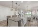 Open-concept kitchen with a large island, farmhouse sink, and dining area flowing into the living room at 12513 Shore Point St, Firestone, CO 80504