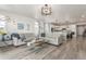Bright living room featuring wood floors, sofas, and open concept to kitchen and dining space at 12513 Shore Point St, Firestone, CO 80504