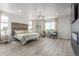 Serene main bedroom with wood accent wall, modern chandelier, and large windows for ample natural light at 12513 Shore Point St, Firestone, CO 80504