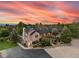 Stunning brick home featuring professional landscaping and a tranquil pond highlighted by a colorful sunset at 10145 Meadow Run, Parker, CO 80134