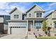 Charming two-story home featuring a two-car garage and a welcoming porch with a vibrant orange door at 21097 E 62Nd Dr, Aurora, CO 80019