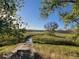 Scenic nature trail with a wooden bridge, lush greenery, a serene lake, and mountains in the distance at 3880 E 128Th Way, Thornton, CO 80241