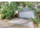 Detached one-car garage with white door and concrete driveway, sheltered by mature trees at 1548 Ulster St, Denver, CO 80220