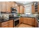 Modern kitchen featuring stainless steel appliances, tile backsplash, granite countertops, and wood cabinets at 2924 Fulton St, Denver, CO 80238