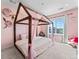 Bright bedroom featuring a canopy bed, pink walls, and a view from the large window at 1425 Hart Ln, Elizabeth, CO 80107