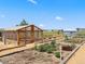 Community garden with wooden greenhouse, raised beds, and surrounding native vegetation on a sunny day at 1425 Hart Ln, Elizabeth, CO 80107
