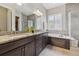 Bathroom featuring double sinks, soaking tub, and glass-enclosed shower for relaxation at 16902 W 94Th Pl, Arvada, CO 80007