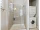 Modern bathroom with glass shower and stacked washer and dryer for convenience at 16902 W 94Th Pl, Arvada, CO 80007