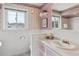 Classic bathroom with a pink vanity, floral wallpaper, and ample natural light from the window at 2225 Linda Vista Dr, Lakewood, CO 80215