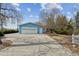 Detached blue garage with white garage door and long driveway surrounded by trees at 2225 Linda Vista Dr, Lakewood, CO 80215