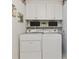 Laundry room with washer and dryer, white cabinets, shelves, and decorative wall art at 2225 Linda Vista Dr, Lakewood, CO 80215
