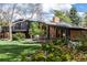 Expansive backyard with a patio, lush greenery, and a unique architectural design of the home at 6975 S Chase Ct, Littleton, CO 80128