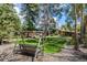 Backyard featuring a wooden swing set, lush greenery, mature trees, and a well-maintained lawn creating a peaceful retreat at 6975 S Chase Ct, Littleton, CO 80128