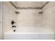White bathtub features tile surround, mosaic accents, and updated black fixtures at 6975 S Chase Ct, Littleton, CO 80128