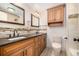 Bathroom with dual sinks, granite countertops, wood cabinets, and modern fixtures at 6975 S Chase Ct, Littleton, CO 80128