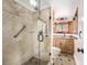 Tiled bathroom with glass shower, stone accents, wood cabinets, and modern fixtures at 6975 S Chase Ct, Littleton, CO 80128