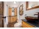Bathroom features dark granite countertop, wood cabinetry, statement mirror, and designer sink at 6975 S Chase Ct, Littleton, CO 80128