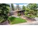 A mid-century modern home with brick and wood accents surrounded by mature trees and manicured landscaping at 6975 S Chase Ct, Littleton, CO 80128