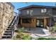 Exterior of the home with a brick facade, upper level deck, covered patio below, and garden with vibrant greenery at 6975 S Chase Ct, Littleton, CO 80128
