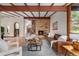 Open living room showcasing exposed beam ceilings, hardwood floors, and a brick fireplace at 6975 S Chase Ct, Littleton, CO 80128