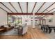 Open-concept living and dining area with hardwood floors and exposed beam ceilings at 6975 S Chase Ct, Littleton, CO 80128