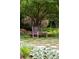 Scenic backyard with a wooden bench under a large tree, surrounded by lush greenery and stone pathways at 1700 E Tufts Ave, Cherry Hills Village, CO 80113